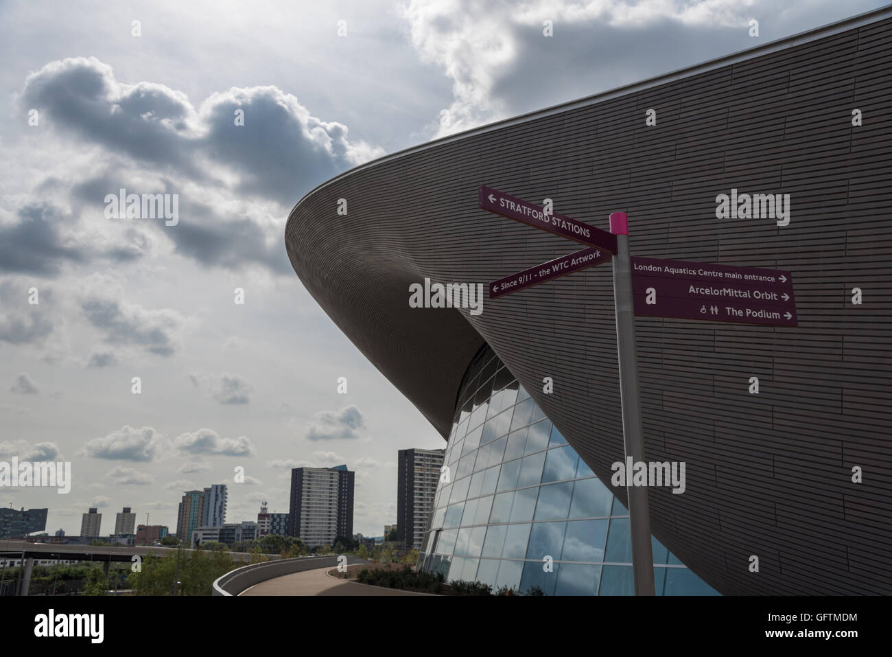 Le toit du centre aquatique olympique contre un ciel atmosphérique. Poteau de signalisation pour les autres installations du parc à l'avant-plan Banque D'Images