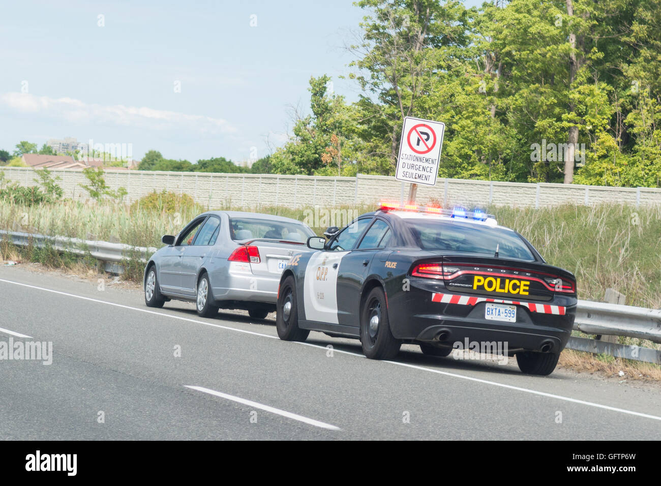 Voiture de police provinciale de l'Ontario de feux clignotants à l'arrêt derrière voiture sur la bande d'arrêt d'urgence à l'extérieur de Toronto, Ontario, Canada Banque D'Images