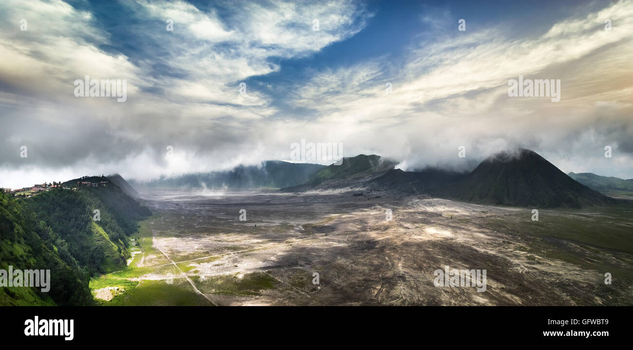 Panorama incroyable sur le Mont Bromo avec volcan actif et village sous ciel nuageux. Paysage de l'île de Java, Indonésie Banque D'Images