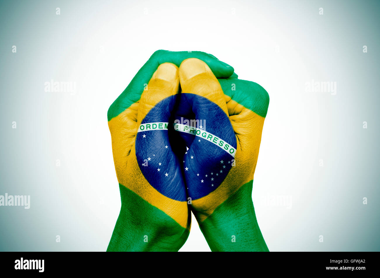 Gros plan des mains d'un jeune homme mis ensemble, avec le drapeau du Brésil sur un fond blanc, avec une légère vig Banque D'Images