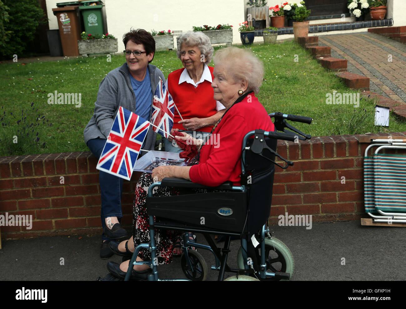 Street Party qui a eu lieu à l'occasion du 90e anniversaire de la reine Elizabeth II - personnes âgées Woman in Wheelchair holding Union Jack Drapeaux et Banque D'Images