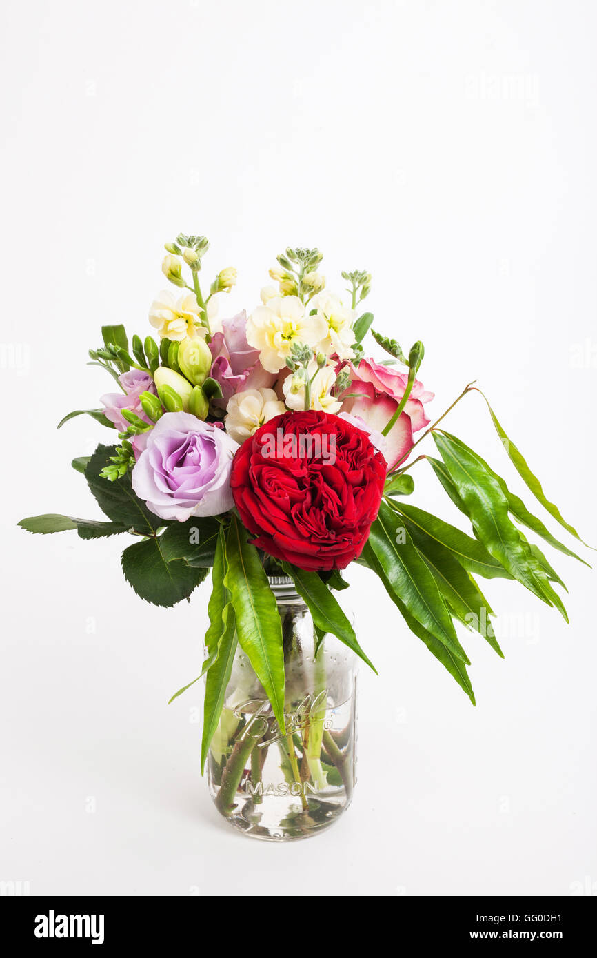 Bouquet de fleurs mixtes de l'Australie et les feuilles dans un bocal en verre Banque D'Images