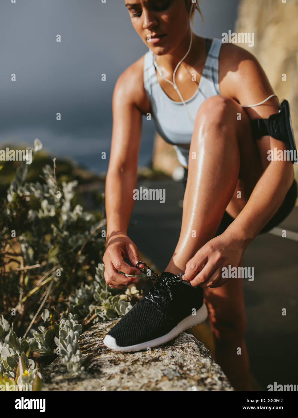 Chaussures de sport à laçage féminin. femme de fitness nouant la dentelle de chaussure avant de courir à l'extérieur, concept de bien-être d'entraînement. Banque D'Images