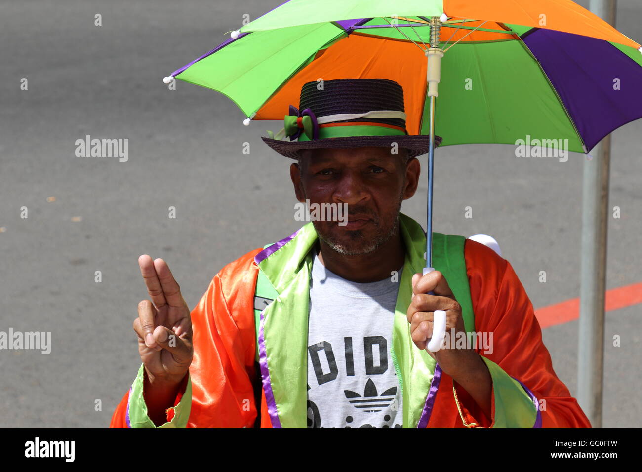 African man wearing vêtements colorés et un chapeau tenant un parapluie à la parade des vins de Stellenbosch 2016 Banque D'Images