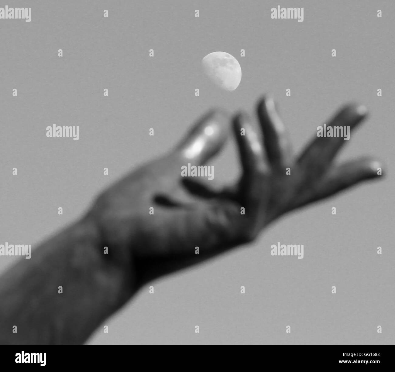 Statue de la main en essayant d'attraper la lune dans le ciel blanc Banque D'Images