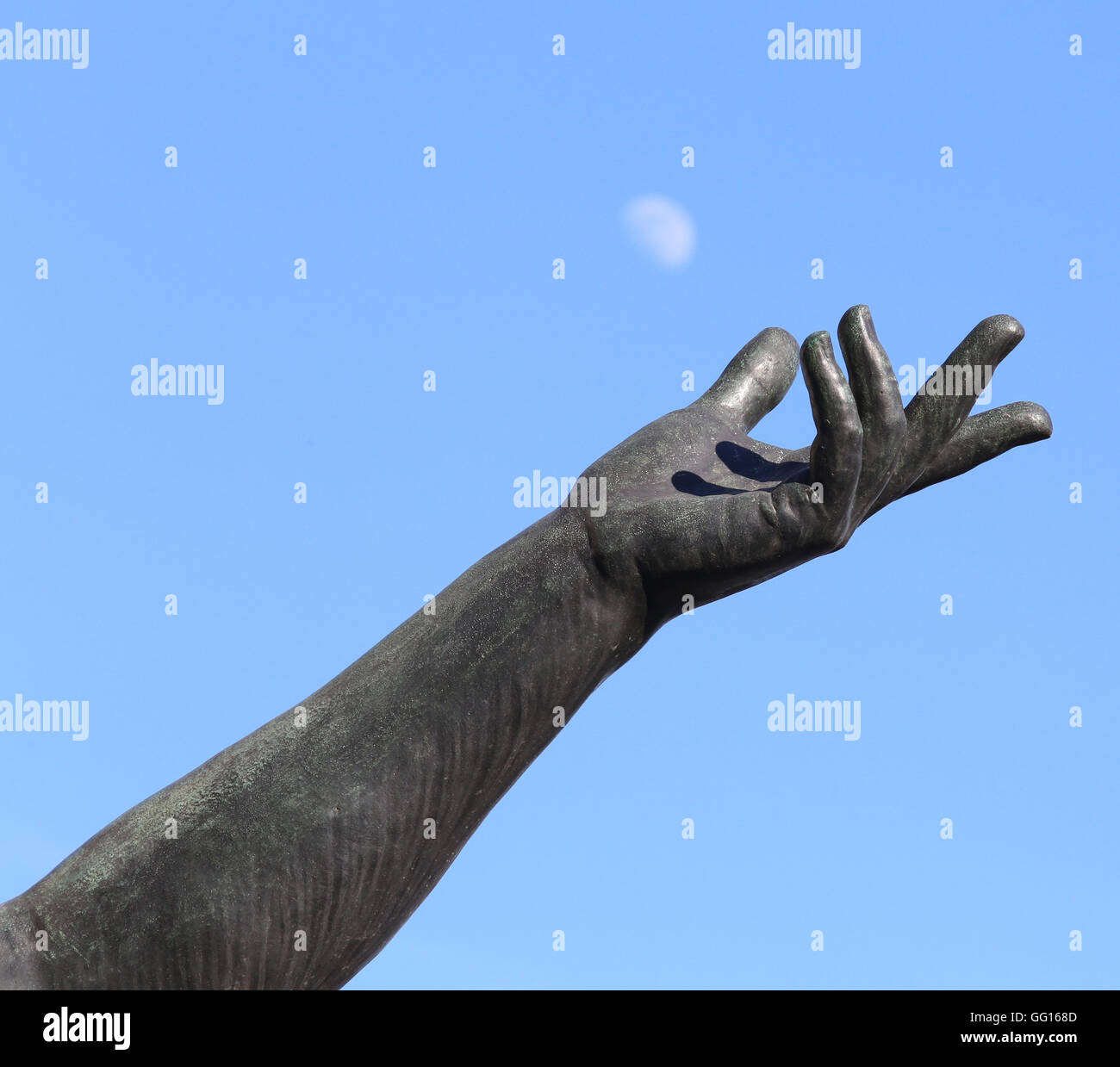 Statue de la main en essayant d'attraper la lune blanche dans le ciel bleu Banque D'Images