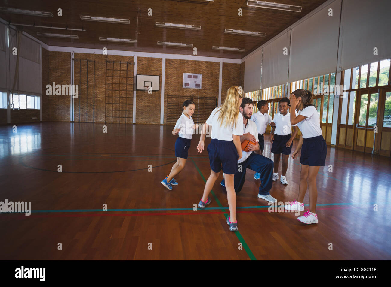 Professeur de sport et l'école les enfants jouant au basket-ball Banque D'Images