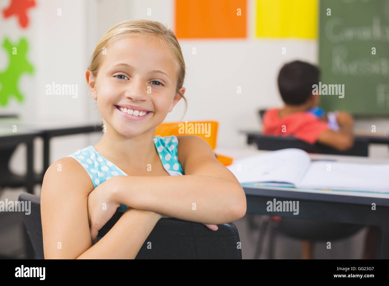 Portrait of cute little girl sitting at desk Banque D'Images