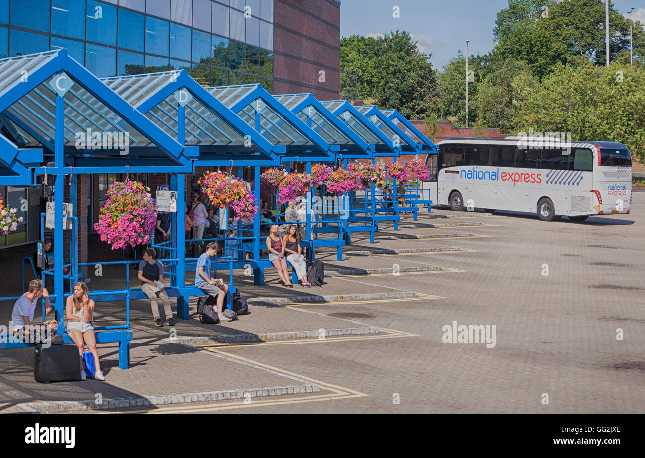 National Express coach à la gare routière de Bournemouth, Bournemouth, Dorset UK avec des gens en attente et des paniers suspendus colorés en juillet - effet hdr Banque D'Images