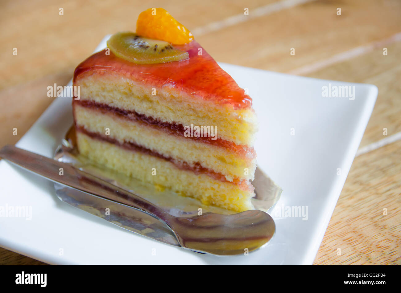 Morceau de gâteau sur une plaque blanche sur table en bois Banque D'Images