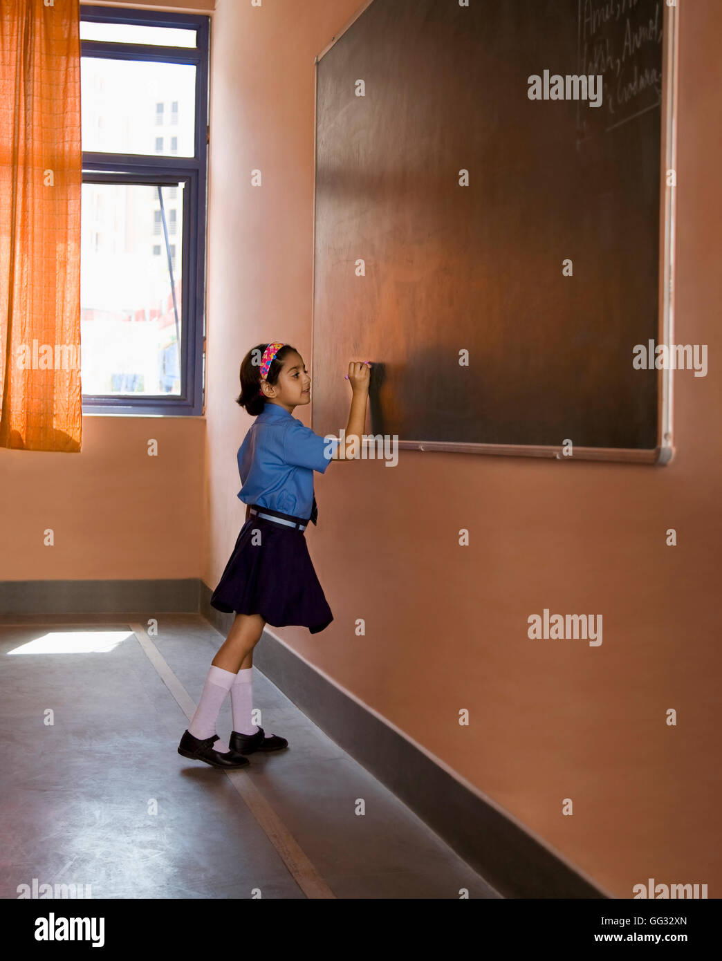 Fille de l'école d'écrire sur le tableau noir Banque D'Images
