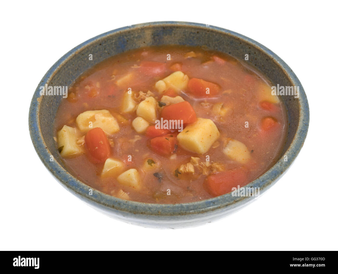 Une portion de style manhattan clam chowder dans un vieux bol en grès sur un fond blanc. Banque D'Images