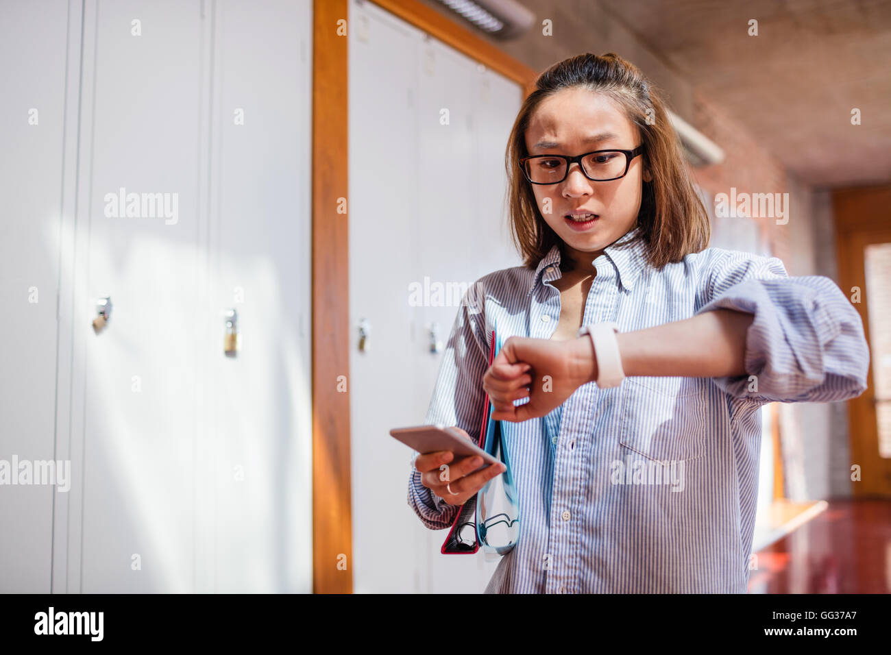 Jeune femme contrôle de moment pendant l'utilisation de téléphone mobile Banque D'Images