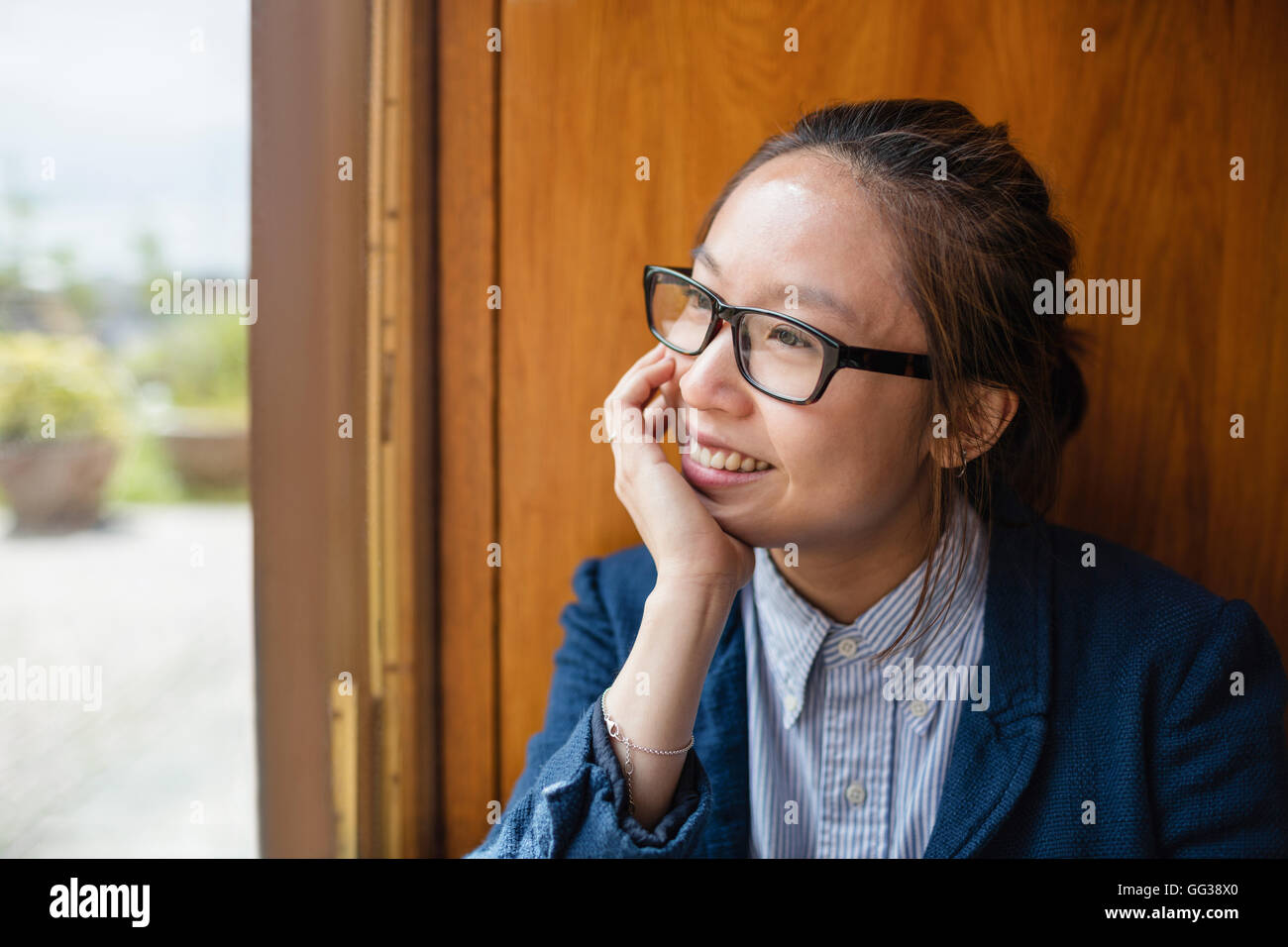 Young woman looking through window Banque D'Images