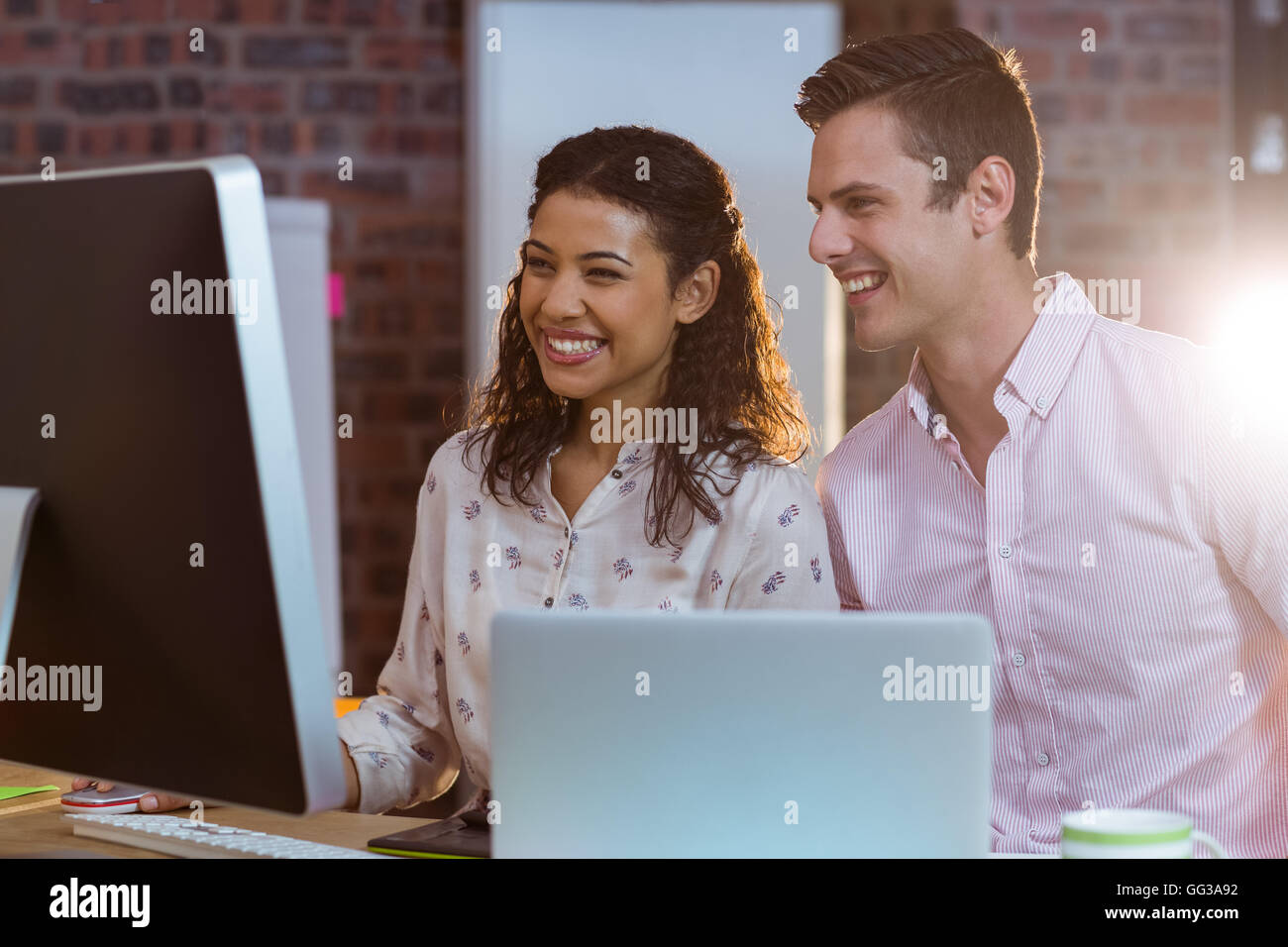 Businesswoman en interaction avec un collègue tout en travaillant sur l'ordinateur Banque D'Images