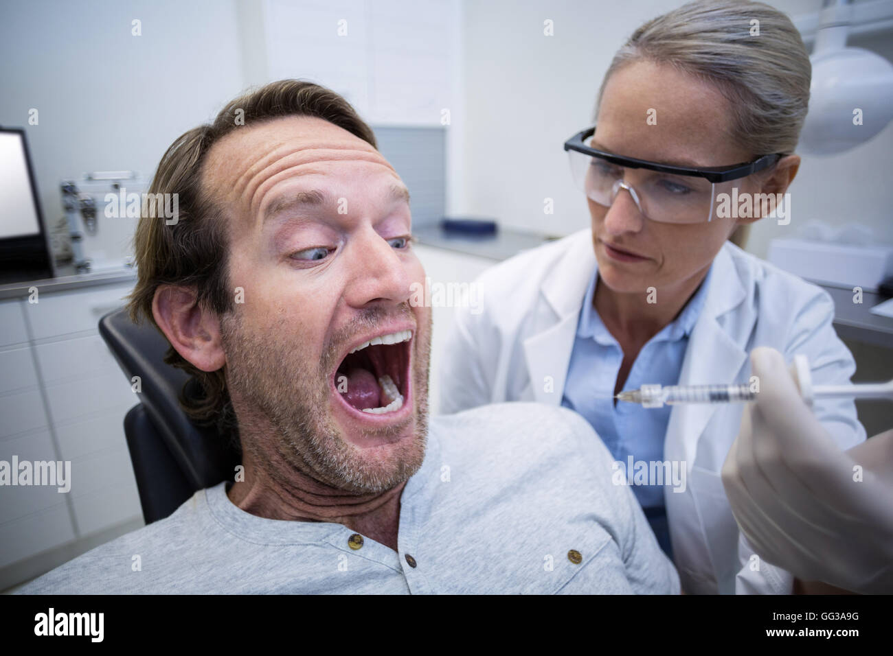 Male patient effrayé pendant un examen dentaire Banque D'Images