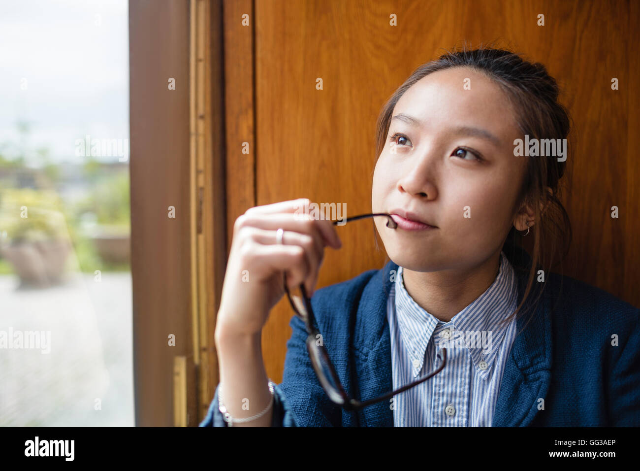 Young woman looking through window Banque D'Images