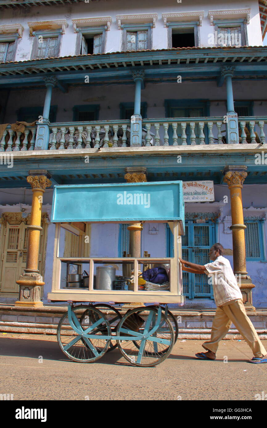 Un vendeur de rue, poussant son échoppe en face des maisons coloniales de Mandvi, Gujarat, Inde Banque D'Images