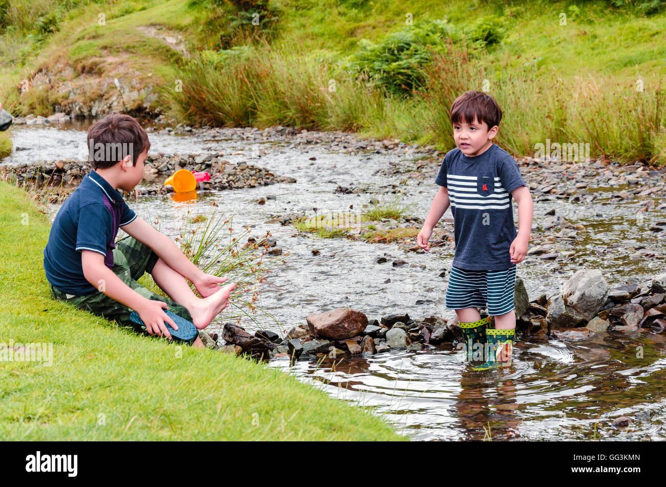 Deux jeunes frères faire un fichu à travers un ruisseau avec des pierres et des roches. Banque D'Images