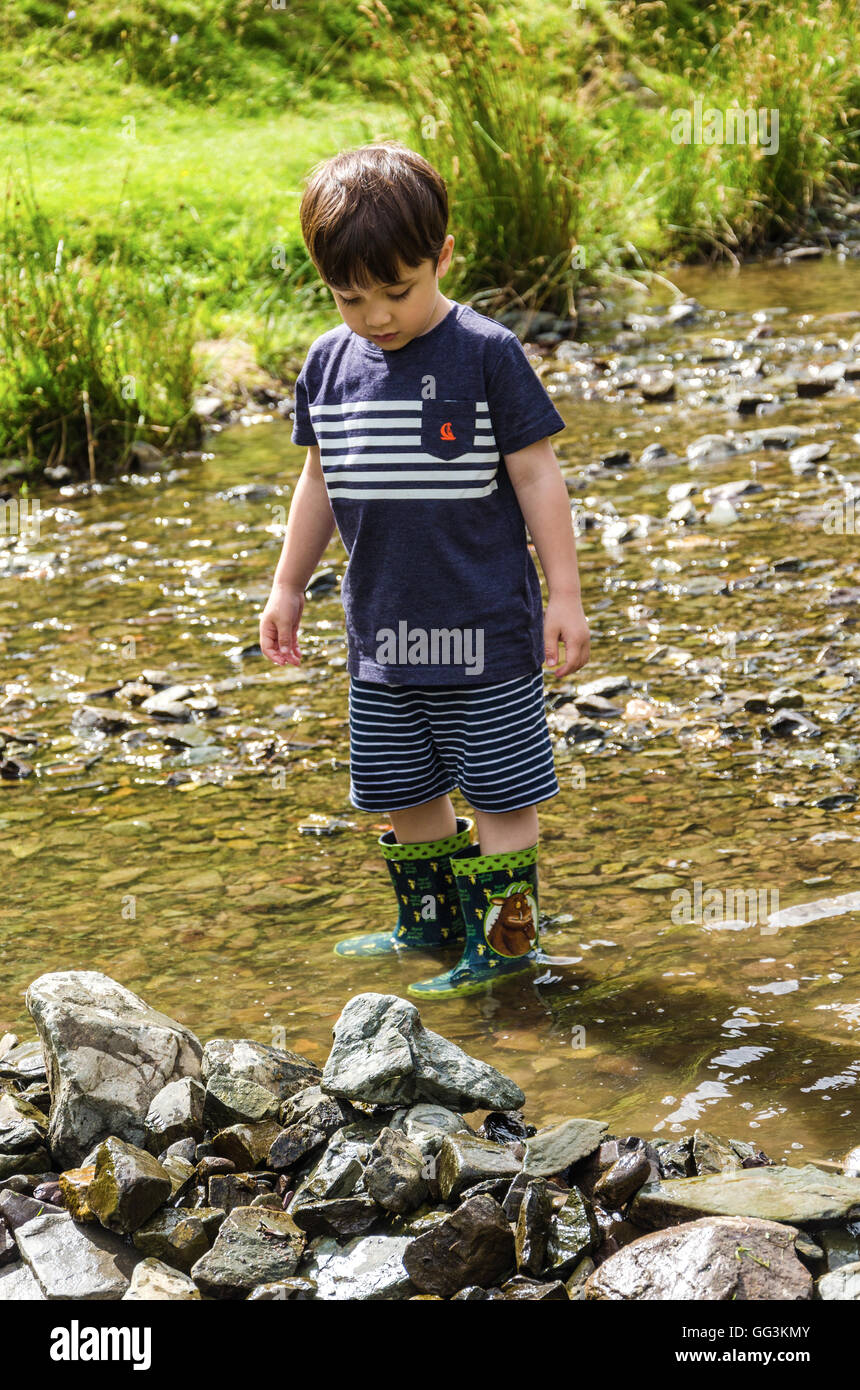 Un jeune garçon joue dans un ruisseau. Banque D'Images