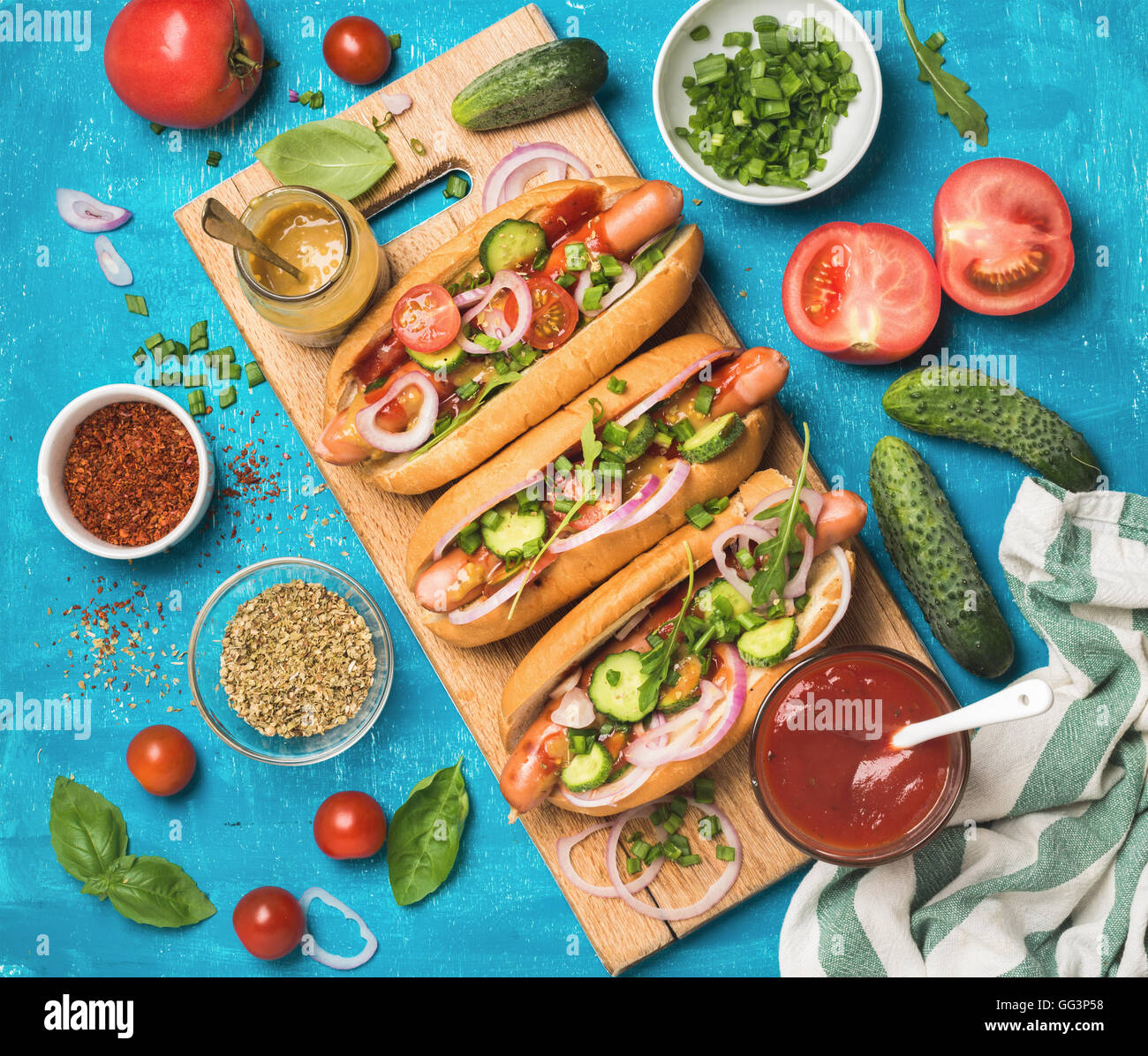 Des hot-dogs avec des légumes frais, épices, le ketchup et la moutarde Banque D'Images