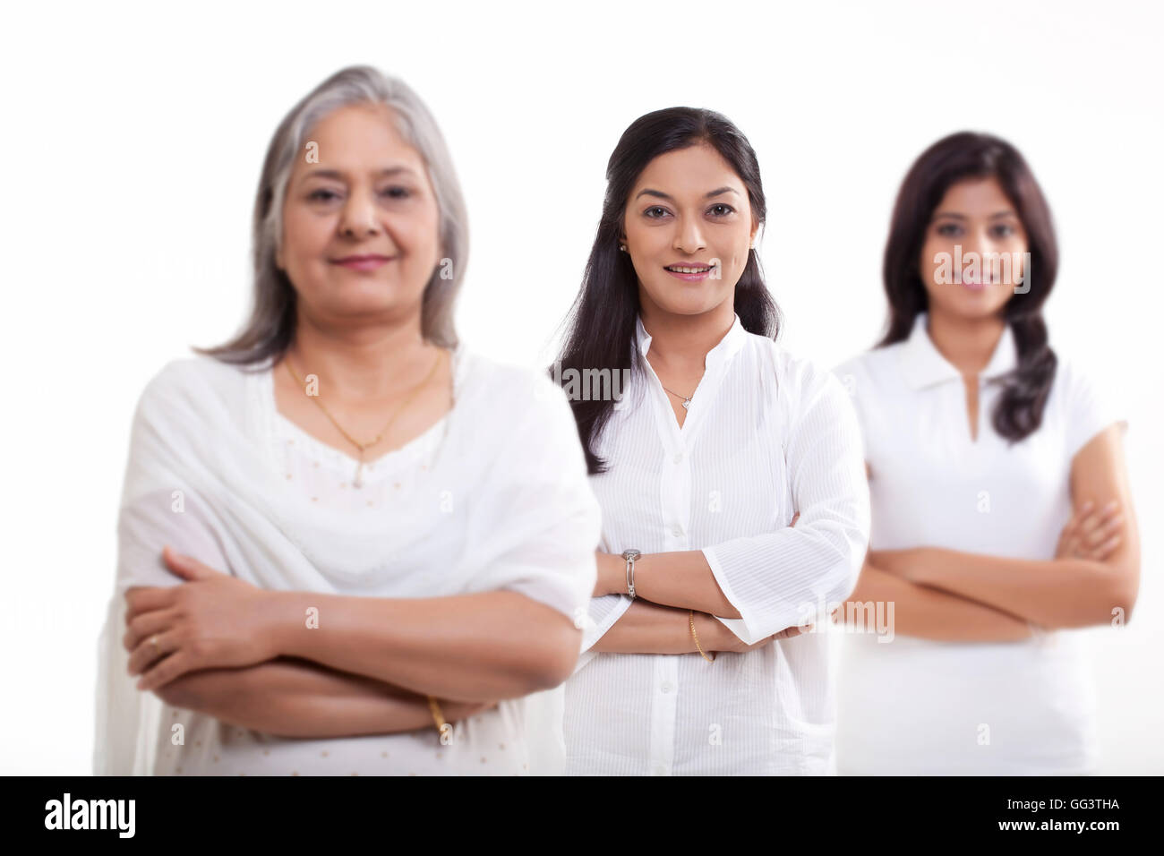 Multi generation family avec les bras croisés sur fond blanc Banque D'Images