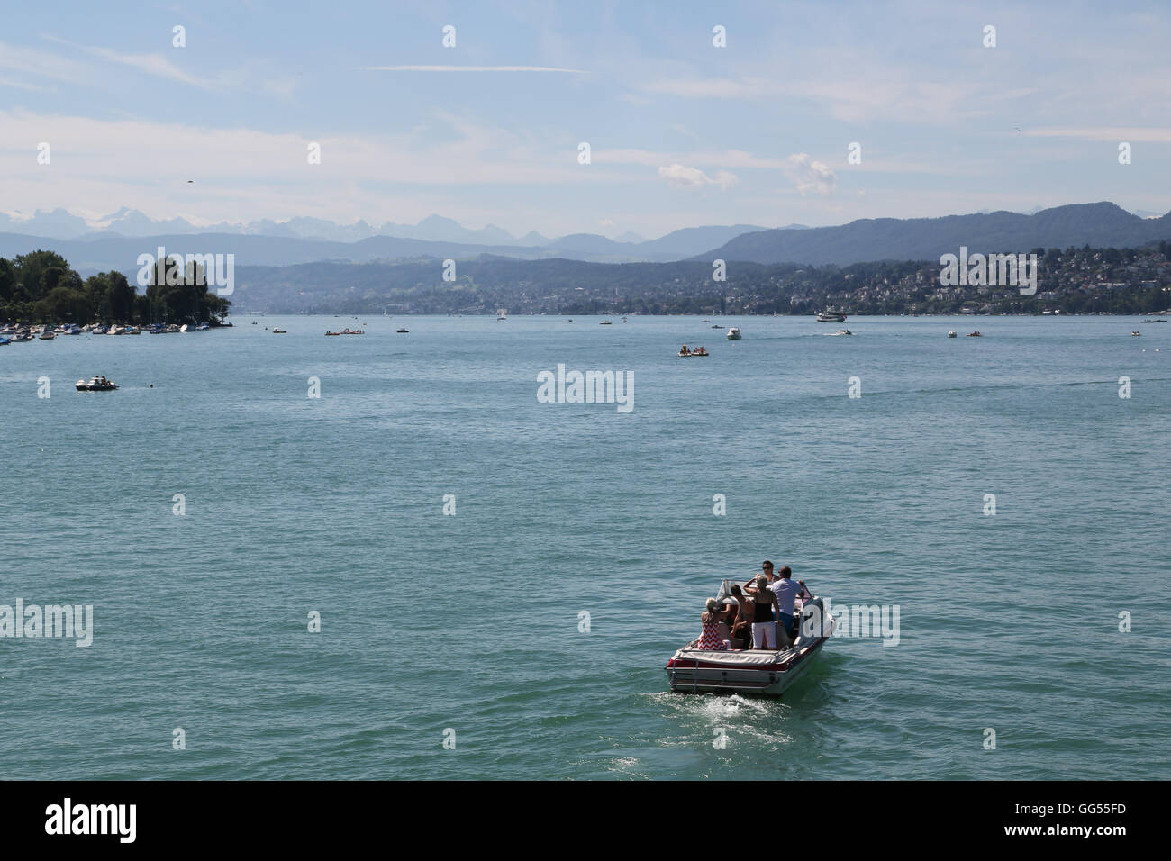 Un bateau fait son chemin à travers le lac de Zurich à Zurich, Suisse, avec les Alpes en toile de fond par une chaude journée d'été. Banque D'Images