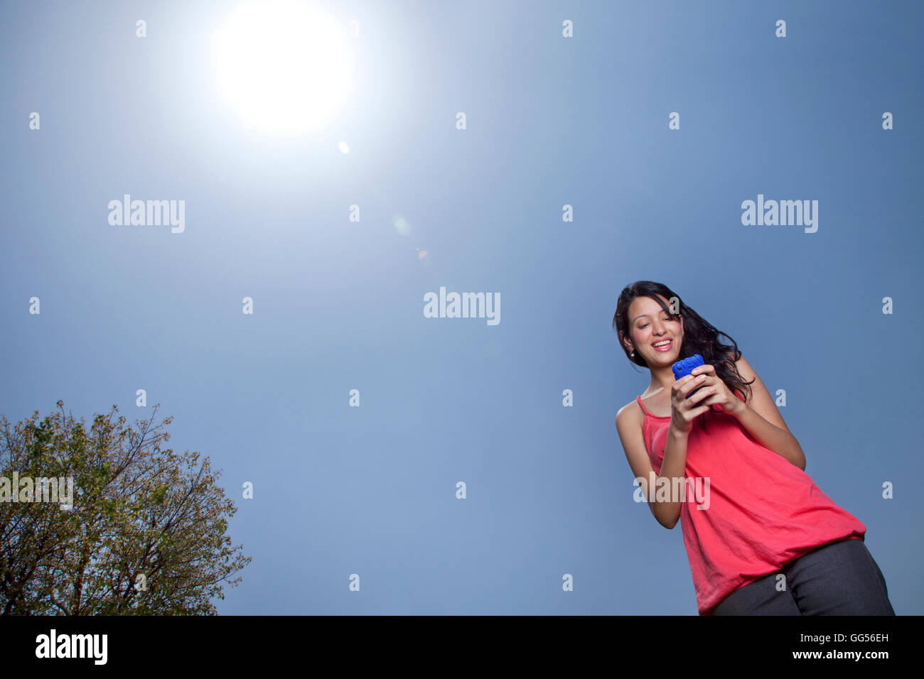Low angle view of woman text messaging on a sunny day Banque D'Images