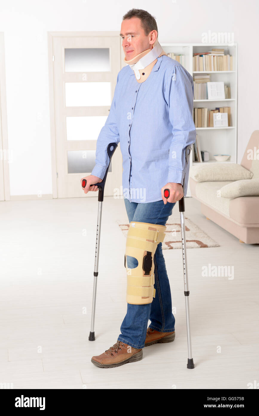 L'homme avec la jambe en neck brace, genou des cages et des béquilles de stabilisation et de soutien Banque D'Images