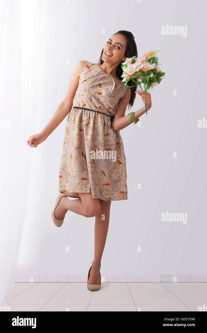 Portrait of happy young woman holding Flowers at home Banque D'Images