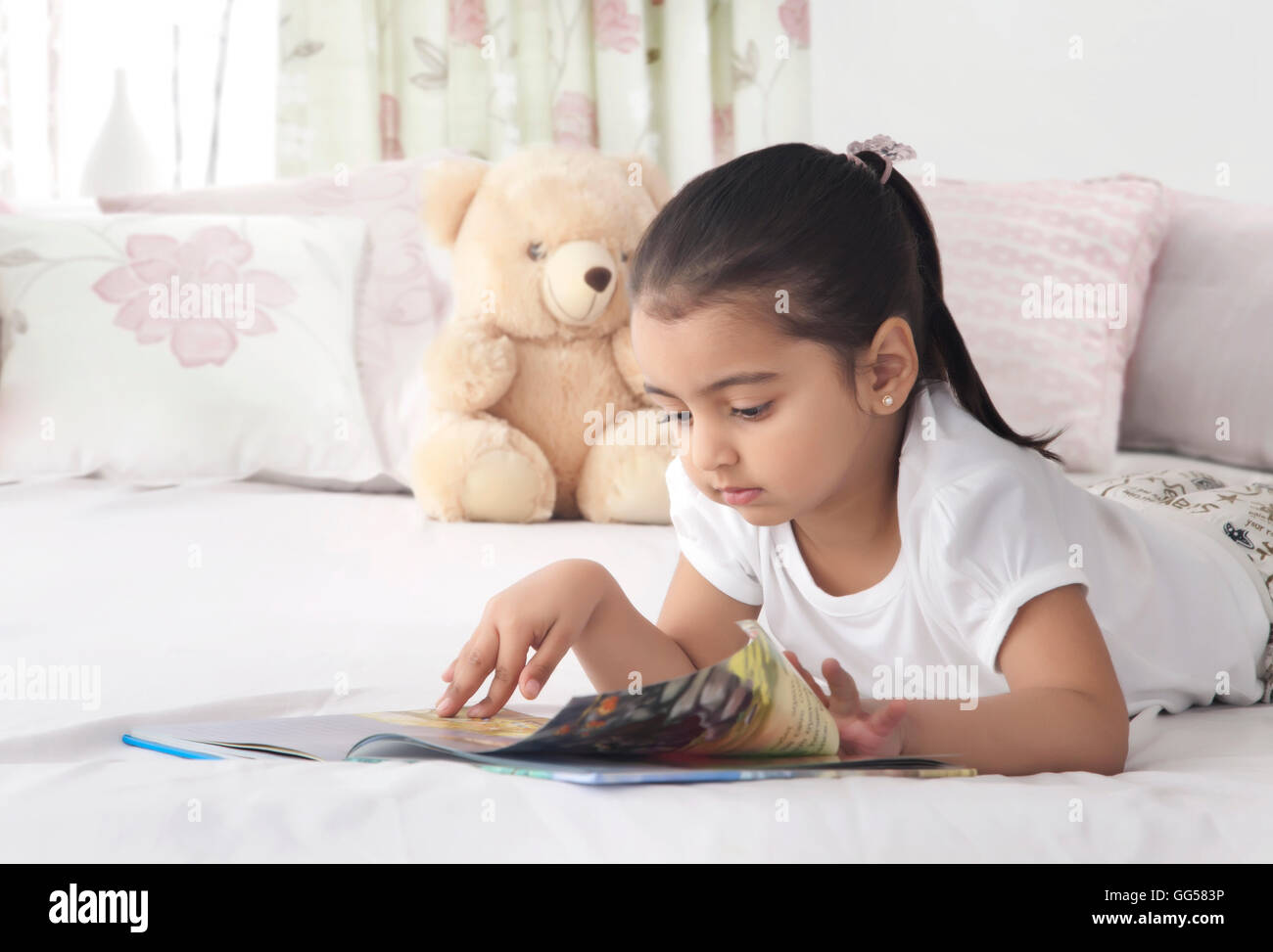 Cute girl tout en tournant la page reading book in bed Banque D'Images