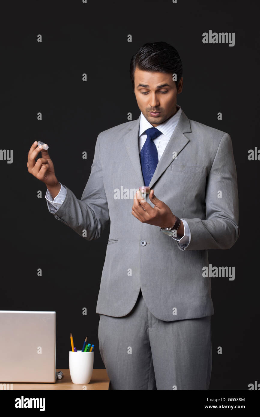 Indian businessman holding baume lèvres pot in office Banque D'Images