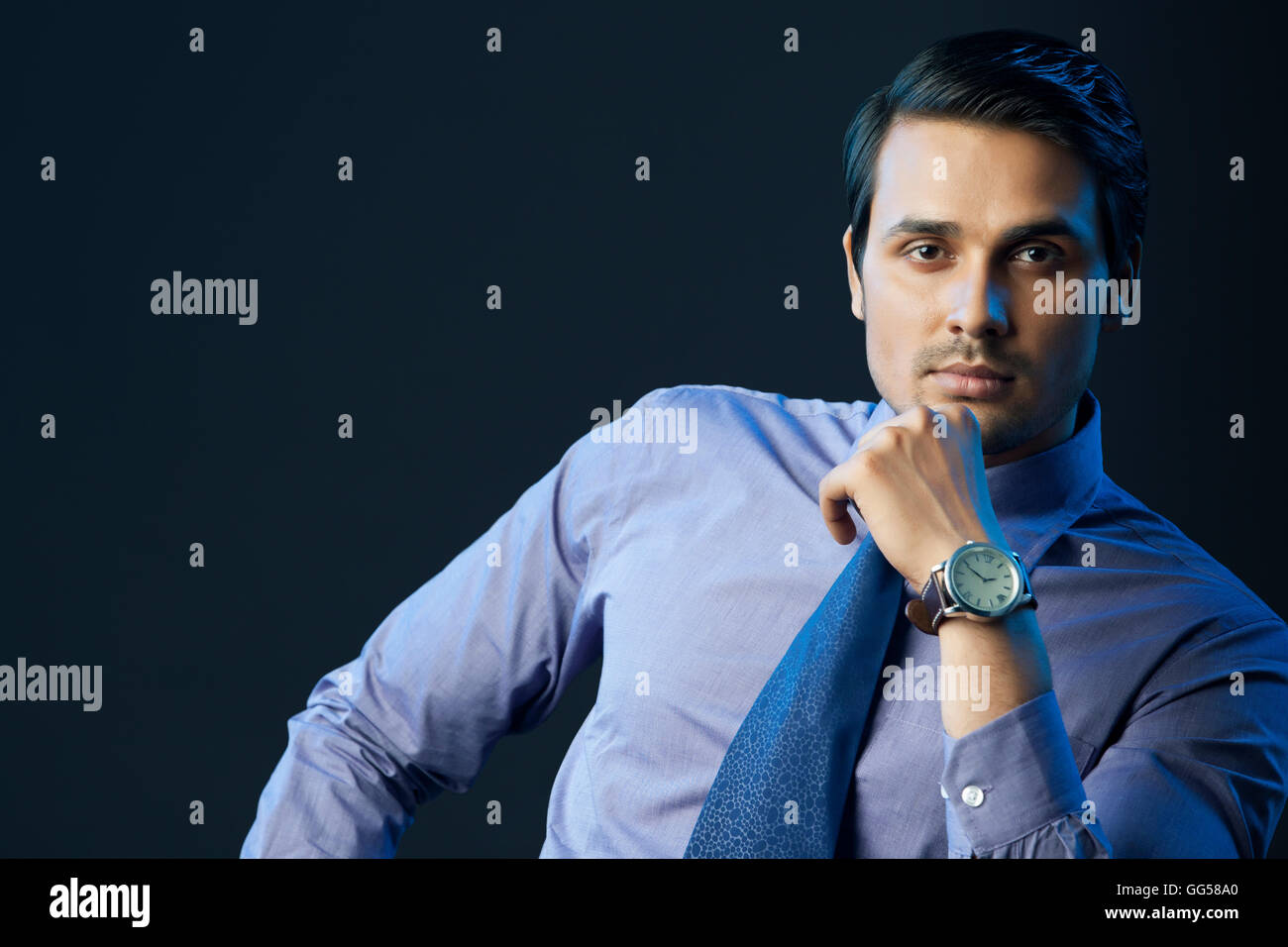 Portrait of smiling businessman with hand on chin sur fond noir Banque D'Images