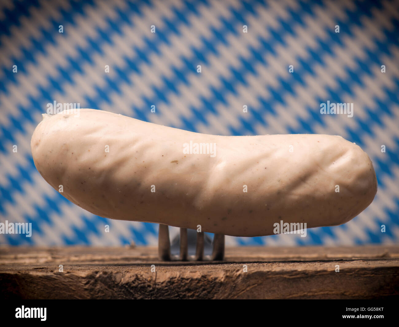 Saucisse de veau bavarois sur une fourche à l'avant d'un drapeau bavarois, selective focus sur la saucisse Banque D'Images