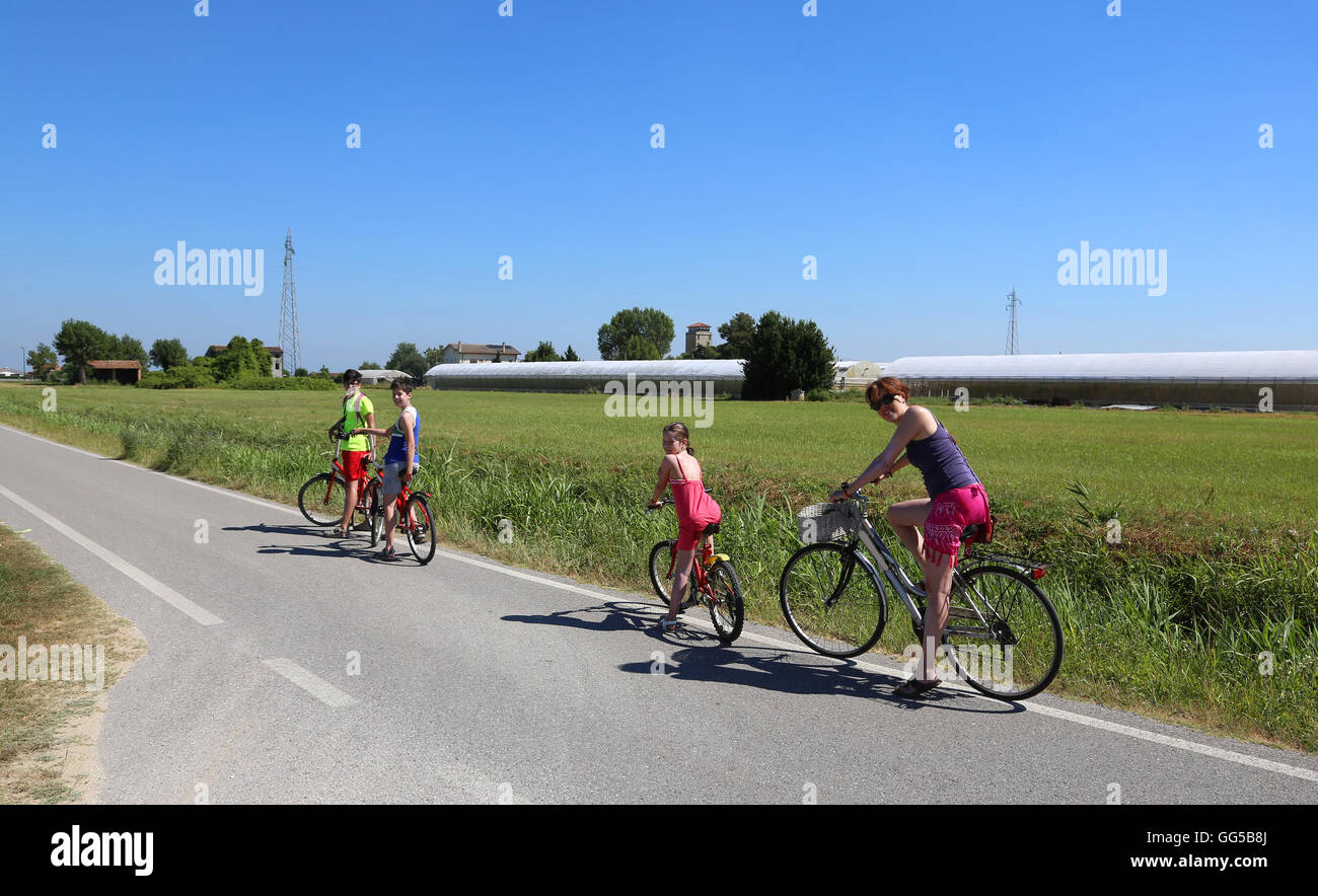 Famille heureuse de quatre personnes faisant un tour à vélo à l'été Banque D'Images