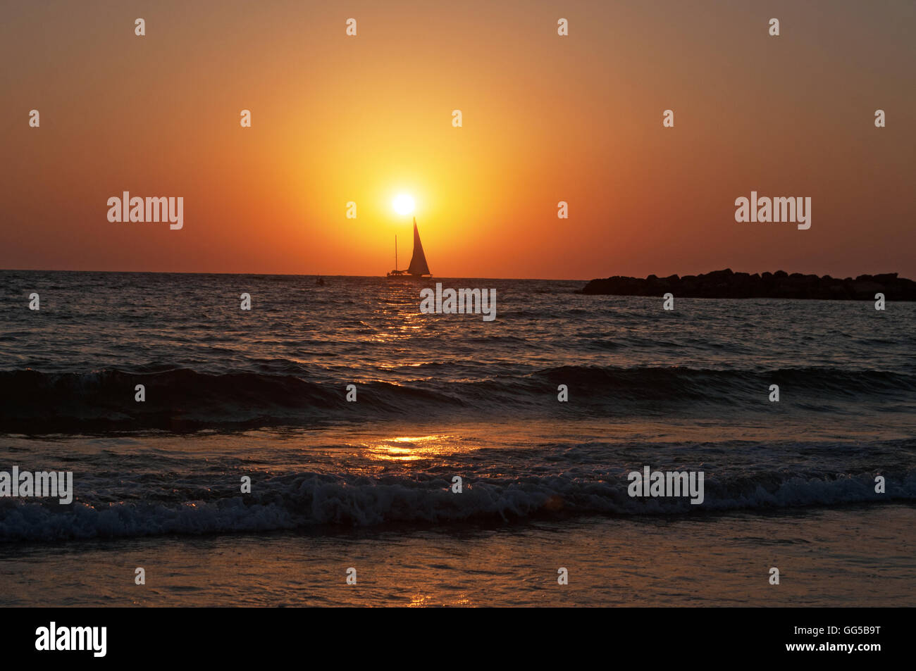 Tel Aviv, Israël, Moyen Orient : la plage, un voilier et la mer Méditerranée au coucher du soleil à la fin d'une belle journée d'été Banque D'Images