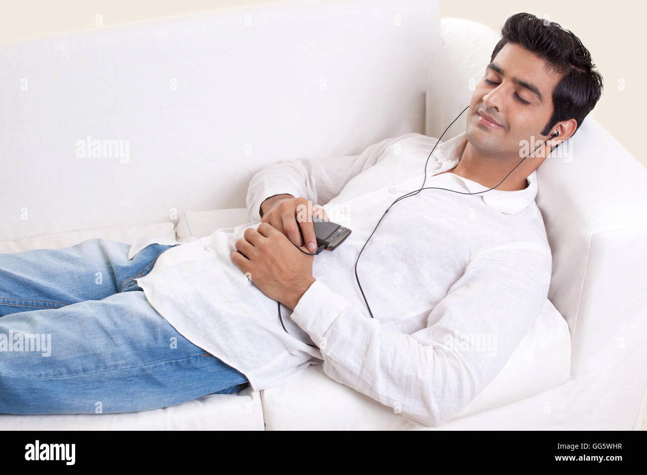 Smart jeune mec allongé sur un canapé, tandis que d'écouter de la musique Banque D'Images