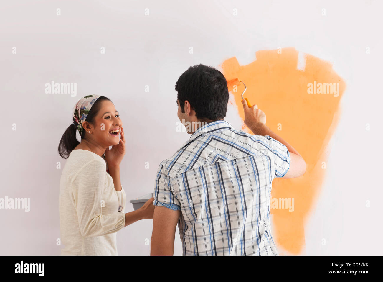 Happy young woman looking at man painting wall Banque D'Images