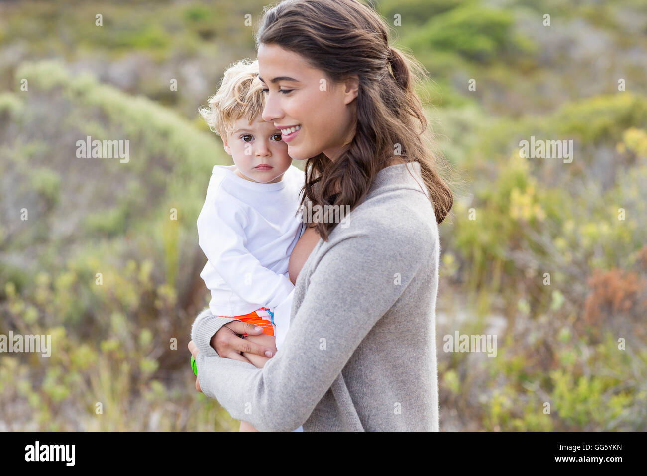 Heureux belle femme portant son bébé Banque D'Images