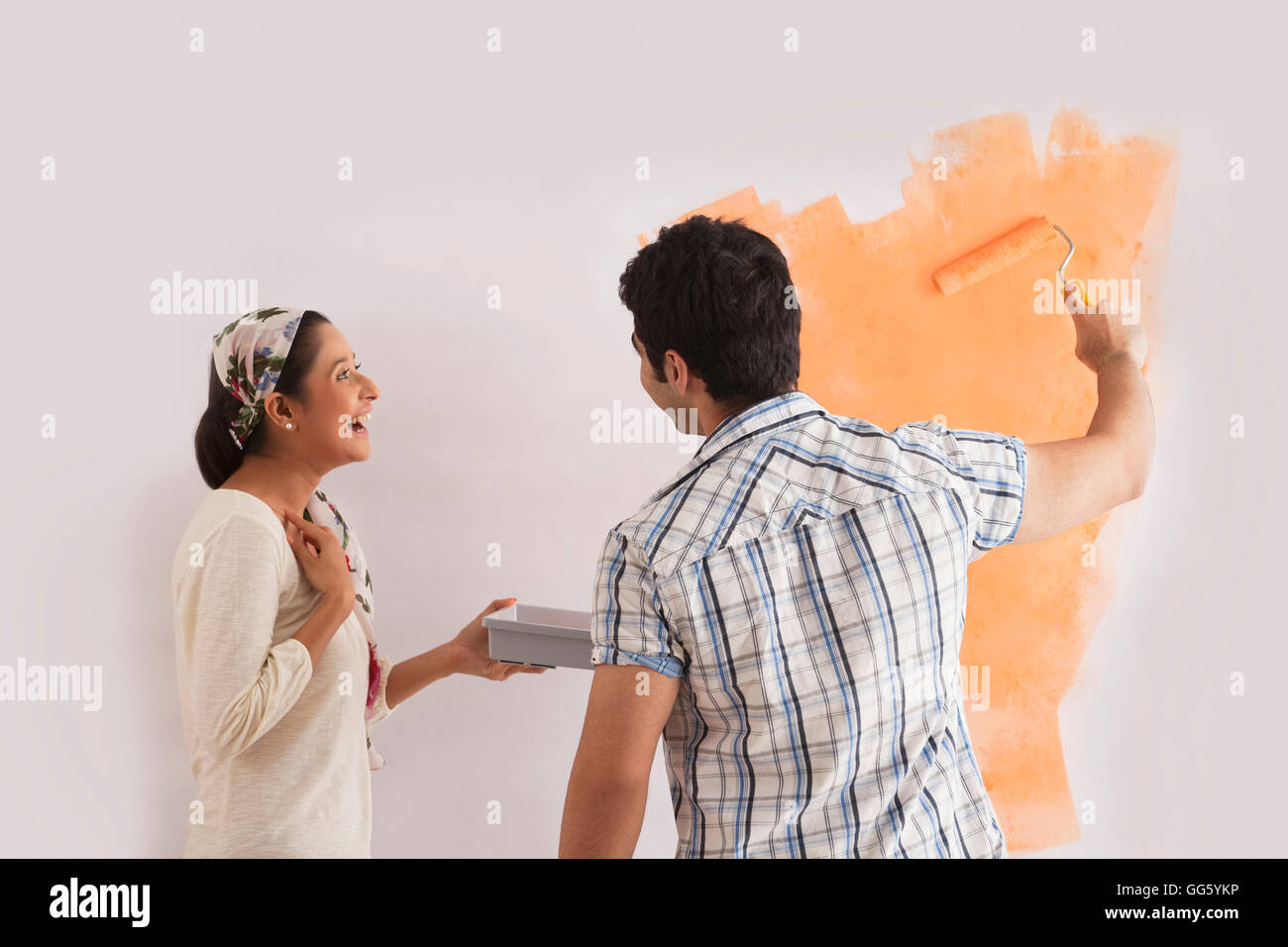 Happy woman looking at man painting wall Banque D'Images