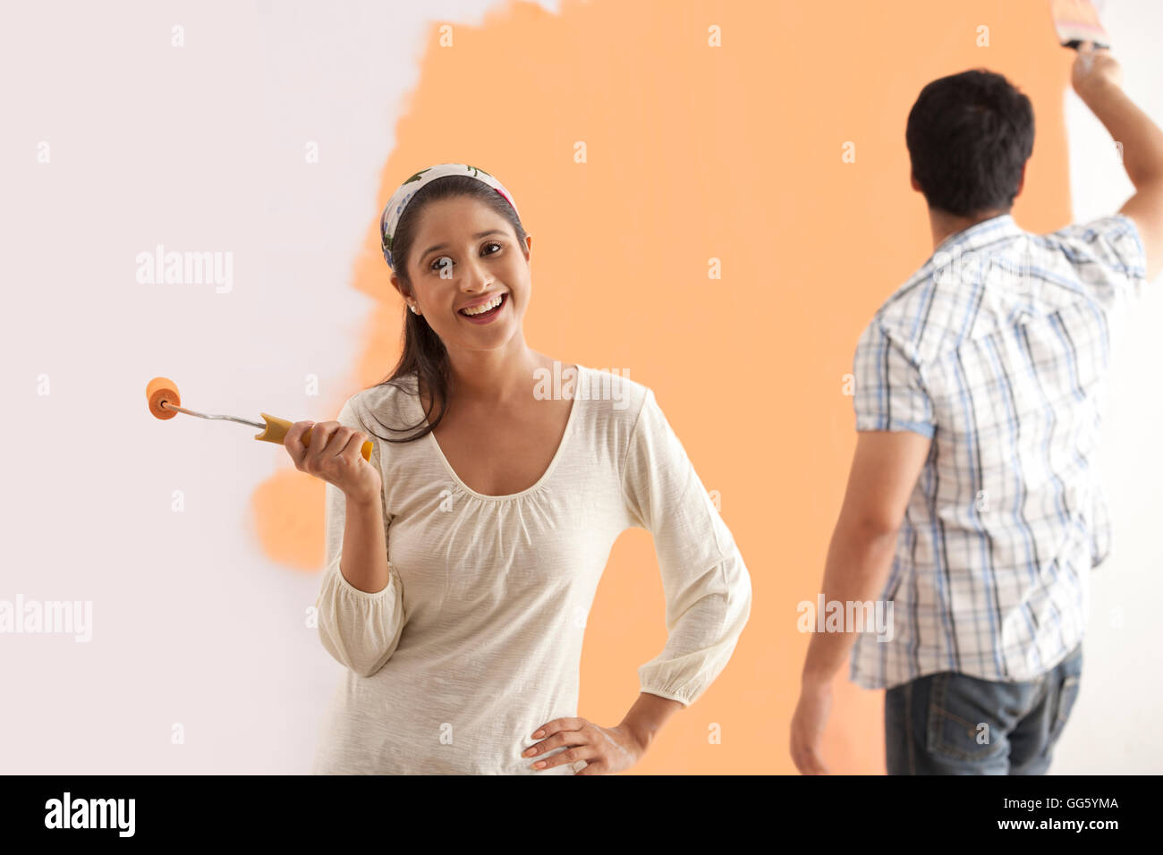 Portrait of smiling young woman with man painting wall en arrière-plan Banque D'Images