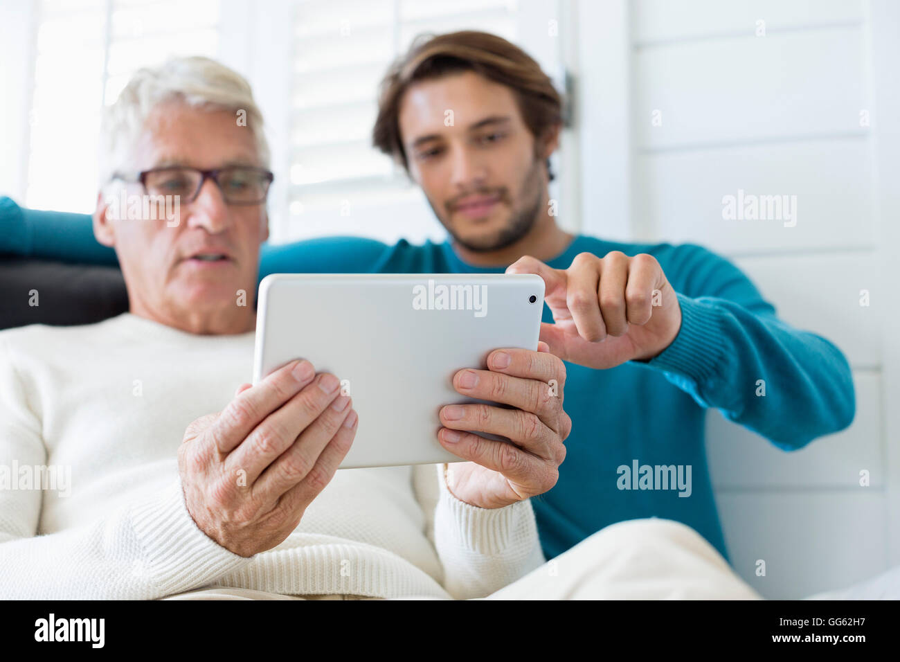 Heureux père et fils using digital tablet in living room Banque D'Images