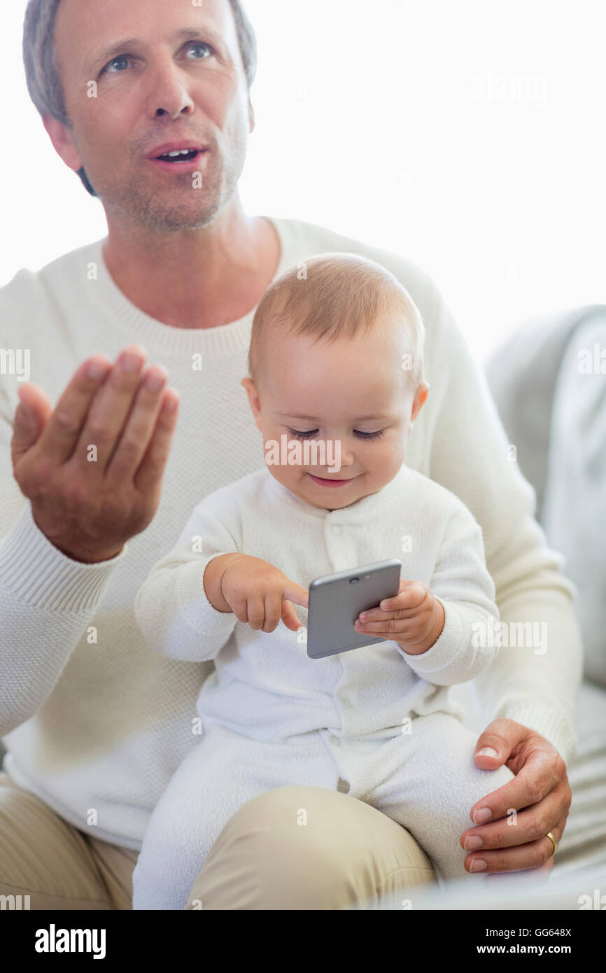Heureux père et sa petite fille jouant avec un téléphone mobile sur la table Banque D'Images