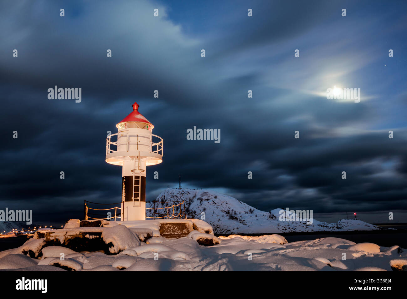 Phare et pleine lune dans la nuit de l'Arctique avec le village de Reine dans l'arrière-plan, Nordland, îles Lofoten, Norvège Banque D'Images