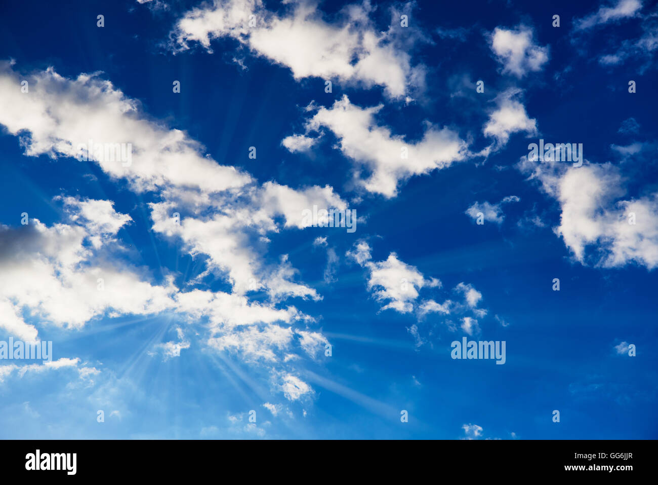 Ciel bleu avec des nuages blancs par lequel le soleil brille avec rayons de soleil visible Banque D'Images