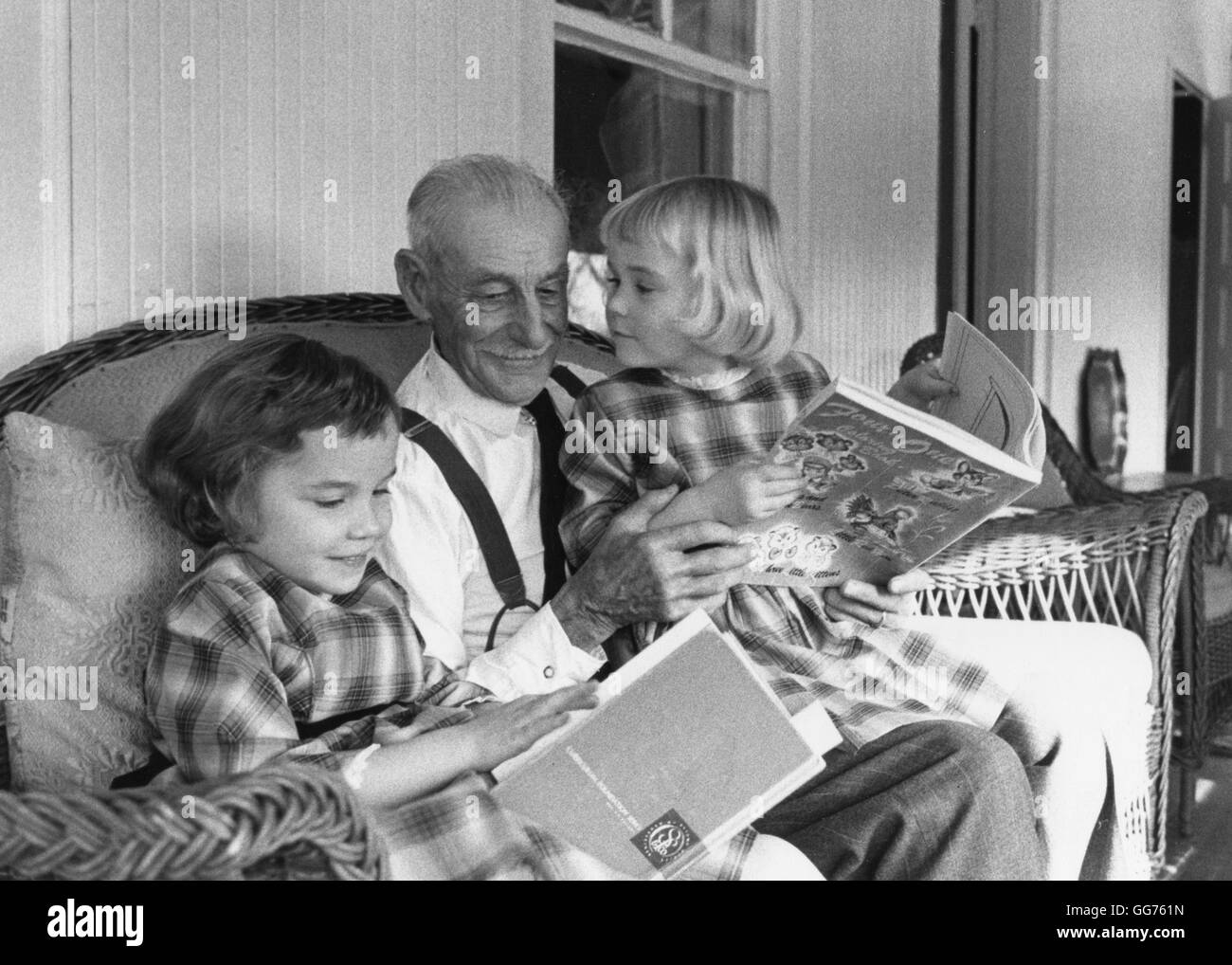 Deux petites filles se sont occupés par leur arrière-grand-père de divertissement avec leurs livres d'images. Banque D'Images