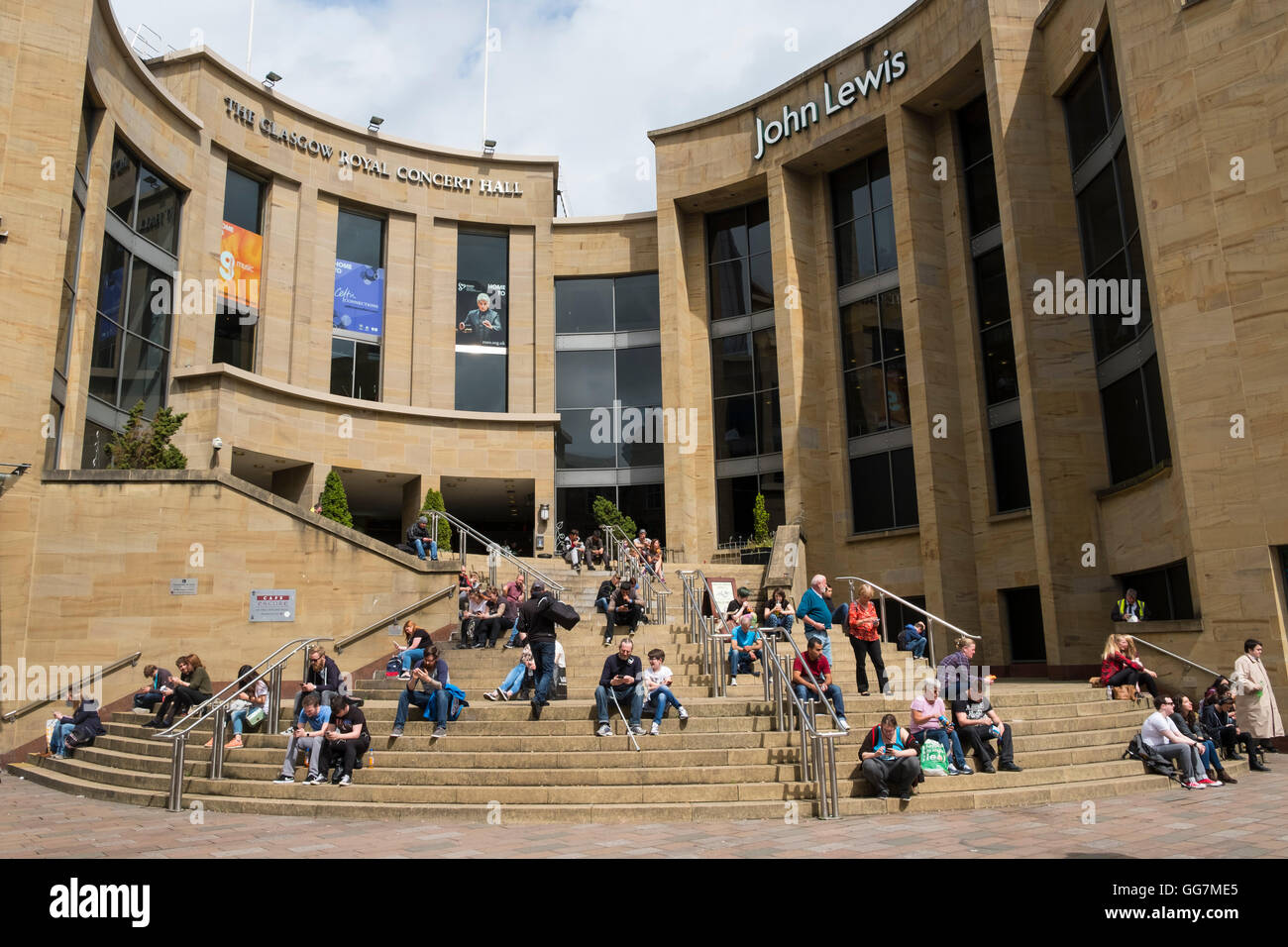 Les gens assis dehors au soleil sur les marches de Glasgow Royal Concert Hall de Glasgow, Ecosse, Royaume-Uni Banque D'Images