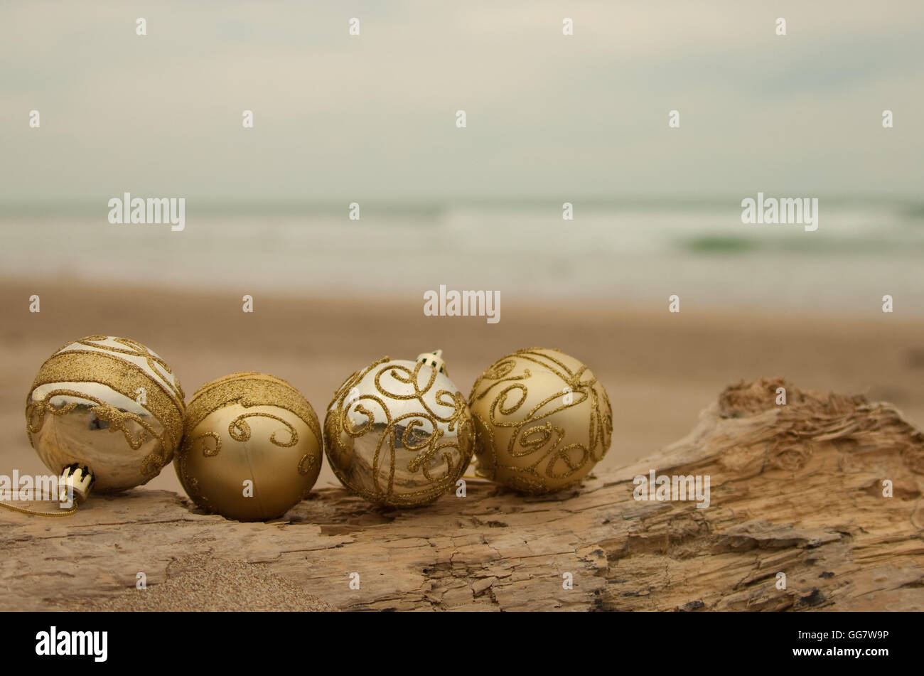 Boules de Noël décoratives disposées en sable avec du bois flotté sur une plage en Nouvelle-Zélande pour un Noël de l'hémisphère Sud d'été Banque D'Images