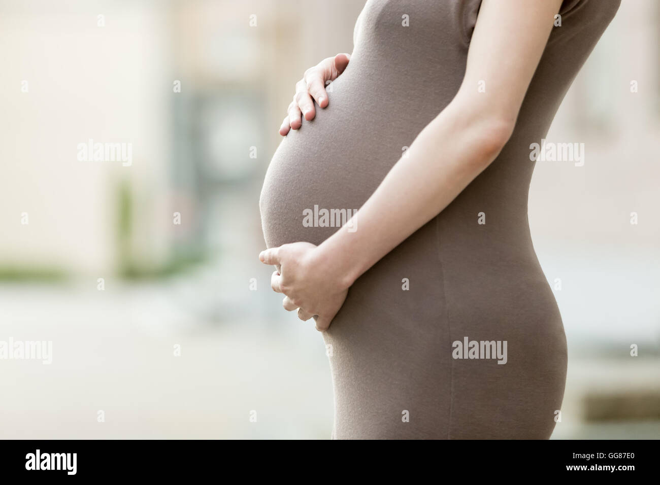 L'amour, famille, grossesse en santé concept. Close-up de ventre d'happy young pregnant woman standing on the street et caressant Banque D'Images