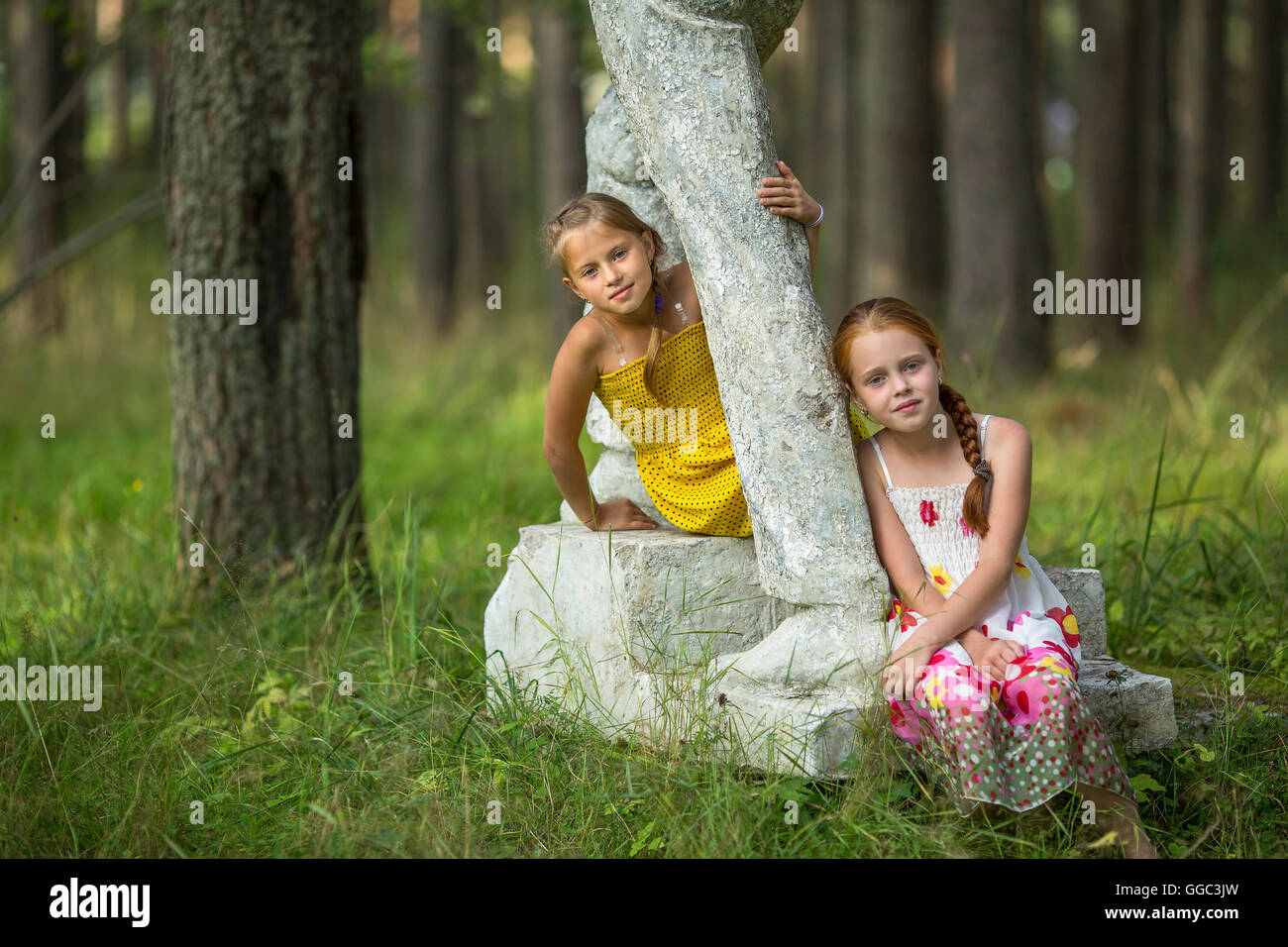 Deux mignonnes petites filles assis sur un socle ancien dans le parc. Banque D'Images